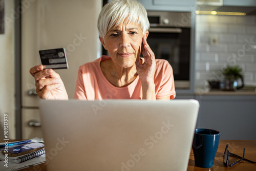 Senior woman shopping online with credit card and laptop at home photo