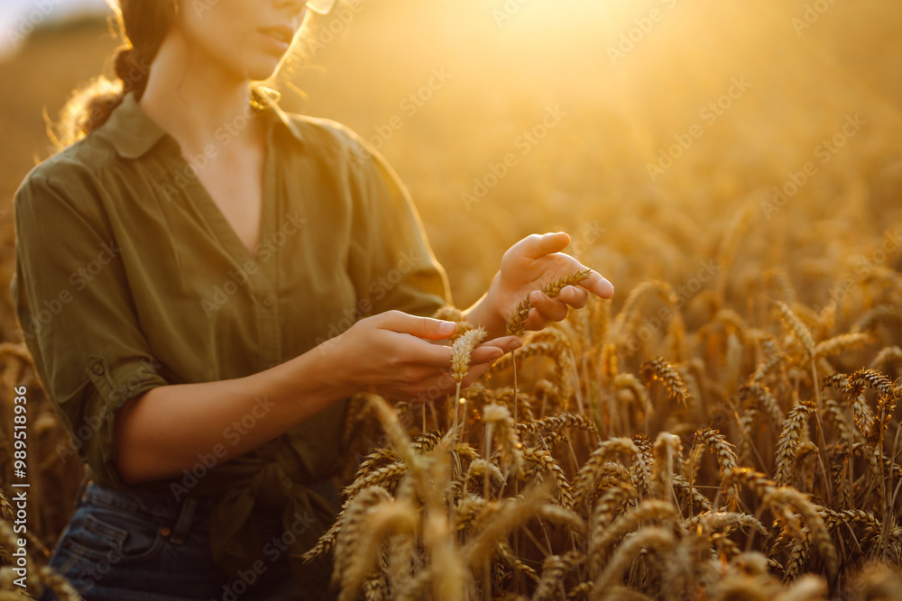 Φωτογραφία A woman examines ripened wheat during sunset in a golden field showcasing the beauty of agriculture and harvest time