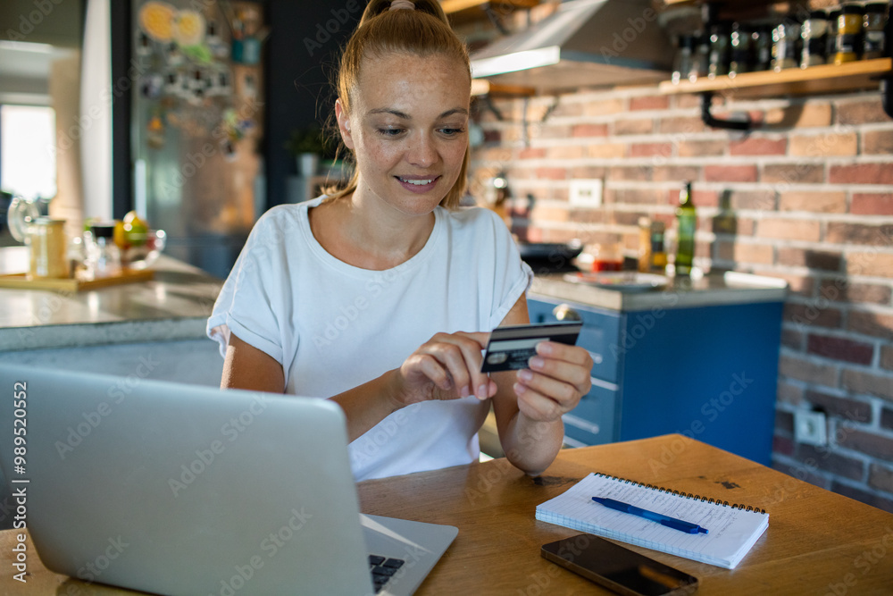 Young woman shopping online with credit card at home kitchen Young woman shopping online with credit card at home kitchen