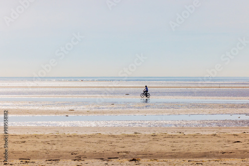 Photography Silhouette of person on bicycle alone at otherwise empty beach on warm sunny day