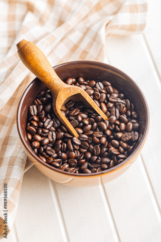 Roasted coffee beans in bowl on white table. Roasted coffee beans in bowl on white table.