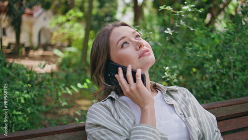 Relaxed girl talking cellphone contemplating green park closeup. Happy woman 