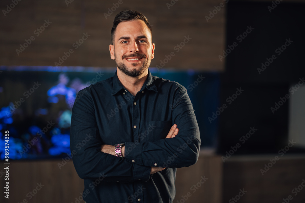 Smiling confident businessman with arms crossed standing at modern office Smiling confident businessman with arms crossed standing at modern office