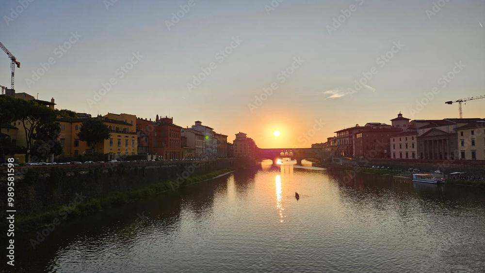Naklejka premium sunset over Ponte Vecchio captures the majestic architecture along the banks of the Arno River in Florence, Italy.
