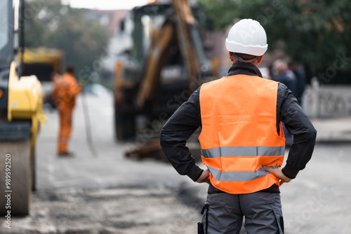 Bild auf Leinwand Construction worker observes roadwork activities at a busy urban site during day
