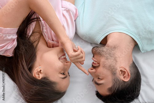 Happy smiling young couple lying on bed