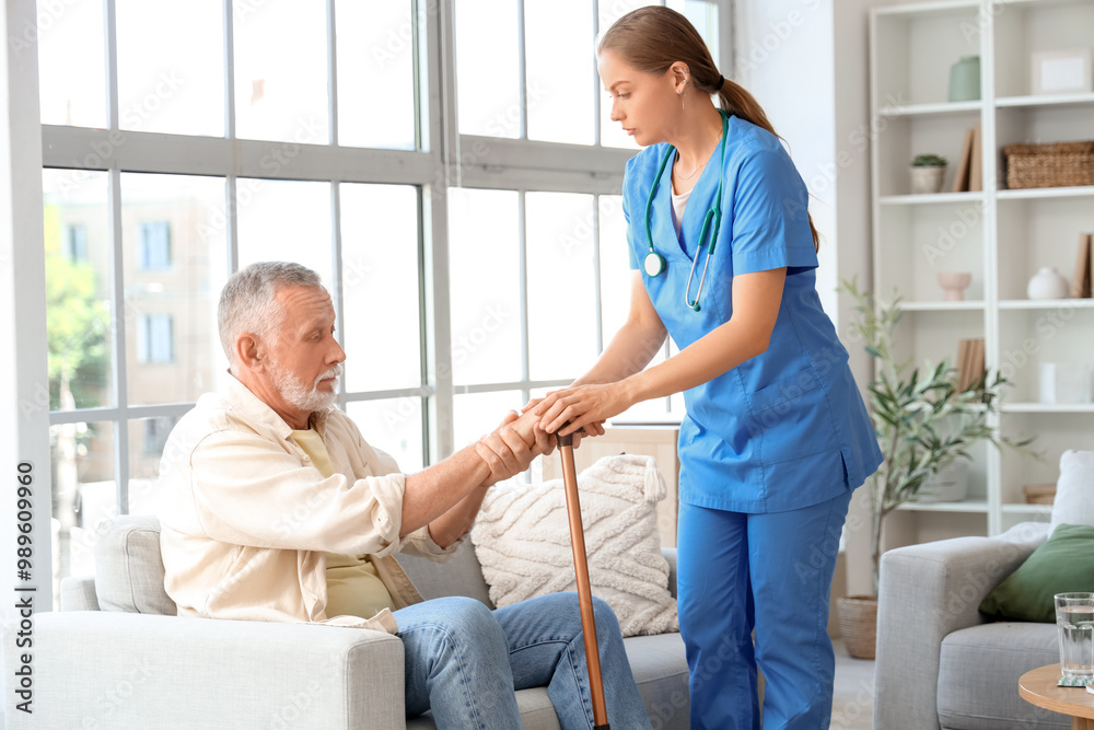 Senior man suffering from Parkinson syndrome with stick and nurse at home