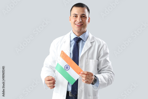 Male doctor with flag of India on grey background. National Doctor's Day celebration photo