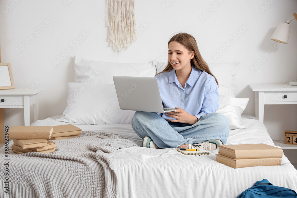 Happy female student with laptop and books studying at home Happy female student with laptop and books studying at home