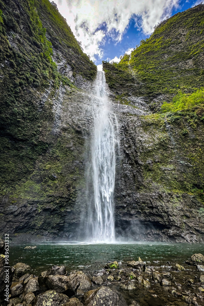 Fototapeta premium Scenic view of Hanakapiai Falls, a waterfall at the end of Hanakapiai Valley hiking trail, Kauai, Hawaii, USA against blue sky with clouds