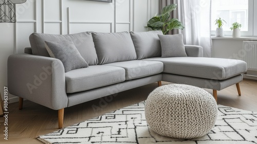 An urban living room featuring a cozy gray sectional sofa, textured decor, and ample natural light photo