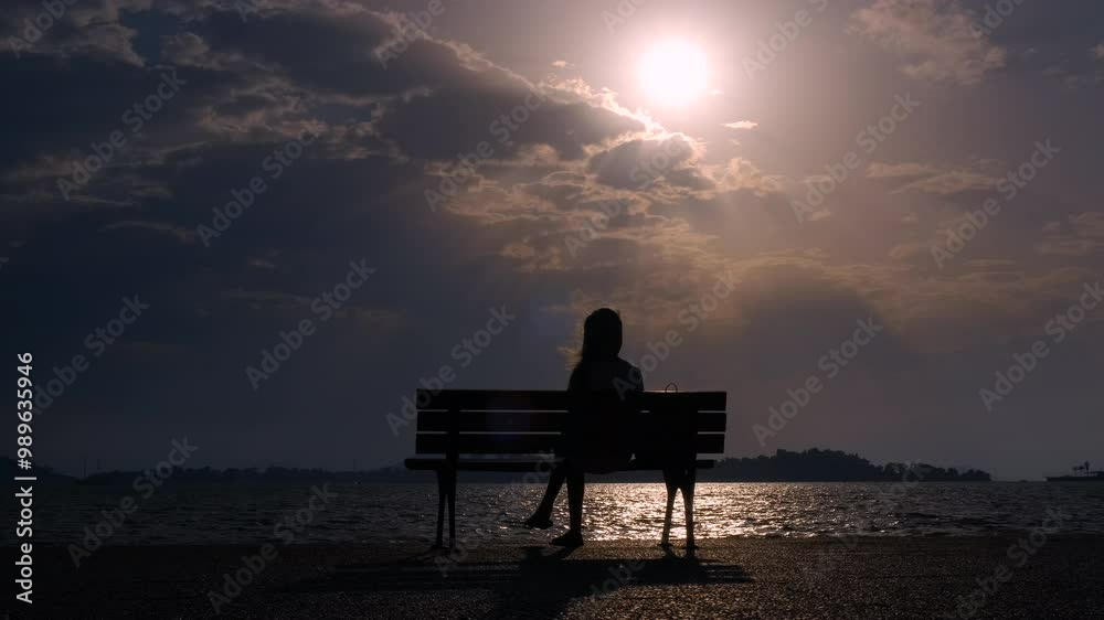 Teen silhouette resting on dusk shore. A view of teen silhouette pass her free time on the beach against beautiful nightfall sky. Teen silhouette resting on dusk shore. A view of teen silhouette pass her free time on the beach against beautiful nightfall sky.