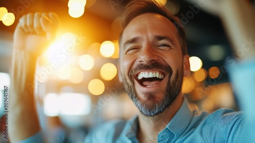 A cheerful man with a beard is seen laughing joyfully in a bright setting, illustrating a moment of happiness and positive energy amidst glowing lights. photo