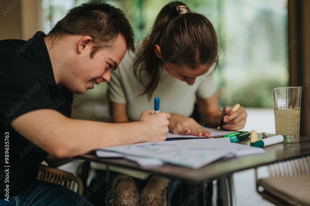 Naklejka premium A joyful moment with young friends, including a male with Down syndrome and a girl in a wheelchair, drawing and painting together at a table.