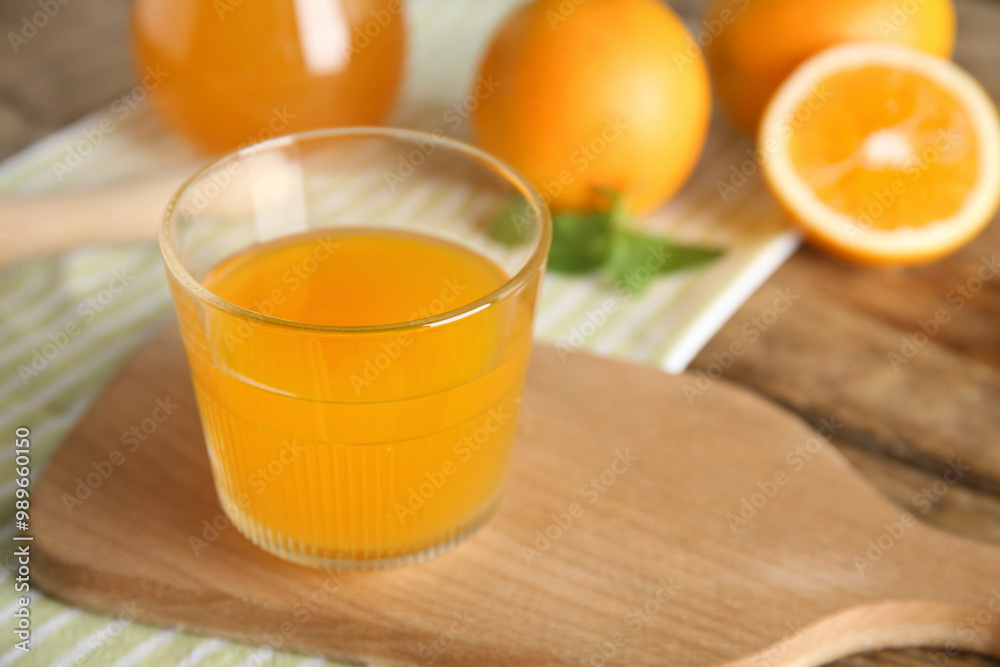 Fototapeta premium Glass of fresh orange juice and fruits on wooden background