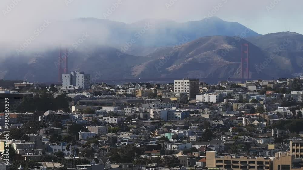 Aerial view of the Golden Gate Bridge surrounded by Fog in San Francisco, California, USA. View from the downtown of San Francisco with houses and buildings in the foreground. Aerial view of the Golden Gate Bridge surrounded by Fog in San Francisco, California, USA. View from the downtown of San Francisco with houses and buildings in the foreground.