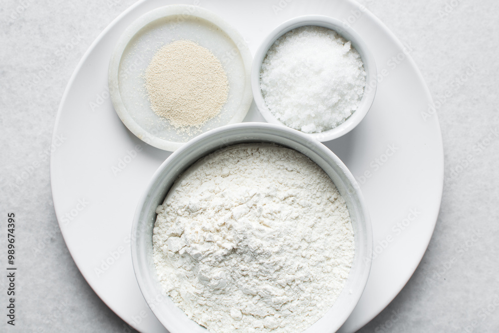 Overhead view of mise en place of ingredients for making nigerian puff-puff, flatlay of flour yeast sugar for puff-puff on a marble countertop, process of making puff-puff or bofrot Overhead view of mise en place of ingredients for making nigerian puff-puff, flatlay of flour yeast sugar for puff-puff on a marble countertop, process of making puff-puff or bofrot