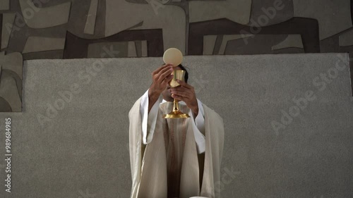 Priest raising the host and wine during the final doxology at a Catholic church mass. photo