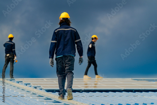 Worker Technicians are working to construct solar panels system on roof. Installing solar photovoltaic panel system. Men technicians walking on roof structure to check photovoltaic solar modules.