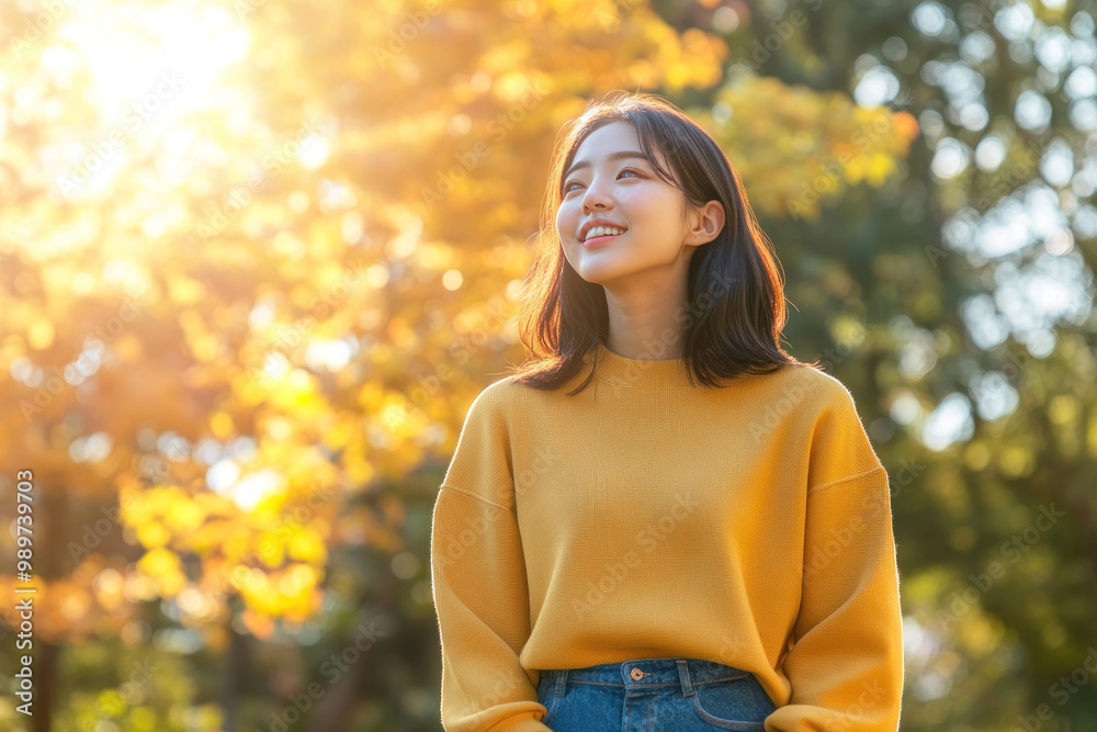 Japanese woman wearing yellow knitted sweatshirt in autumn park at sunny day Japanese woman wearing yellow knitted sweatshirt in autumn park at sunny day