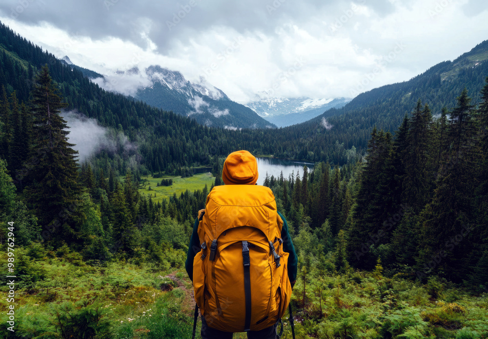 A hiker in a yellow backpack admires a breathtaking mountain landscape, surrounded by lush greenery and mist, evoking a sense of peace and connection with nature. A hiker in a yellow backpack admires a breathtaking mountain landscape, surrounded by lush greenery and mist, evoking a sense of peace and connection with nature.