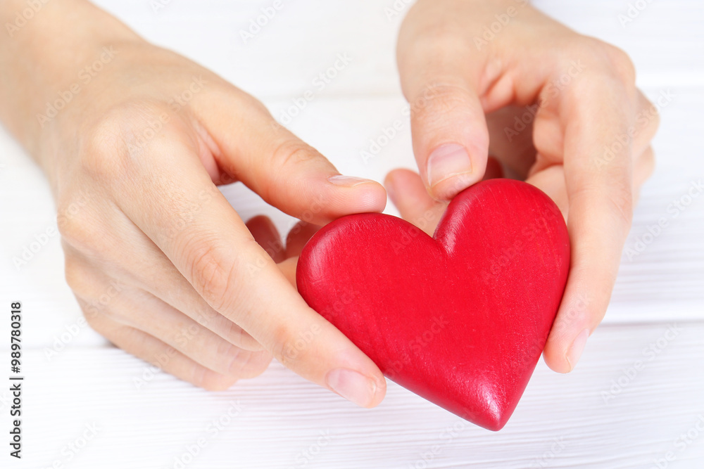 Fototapeta premium Woman holding red heart at white wooden table, closeup