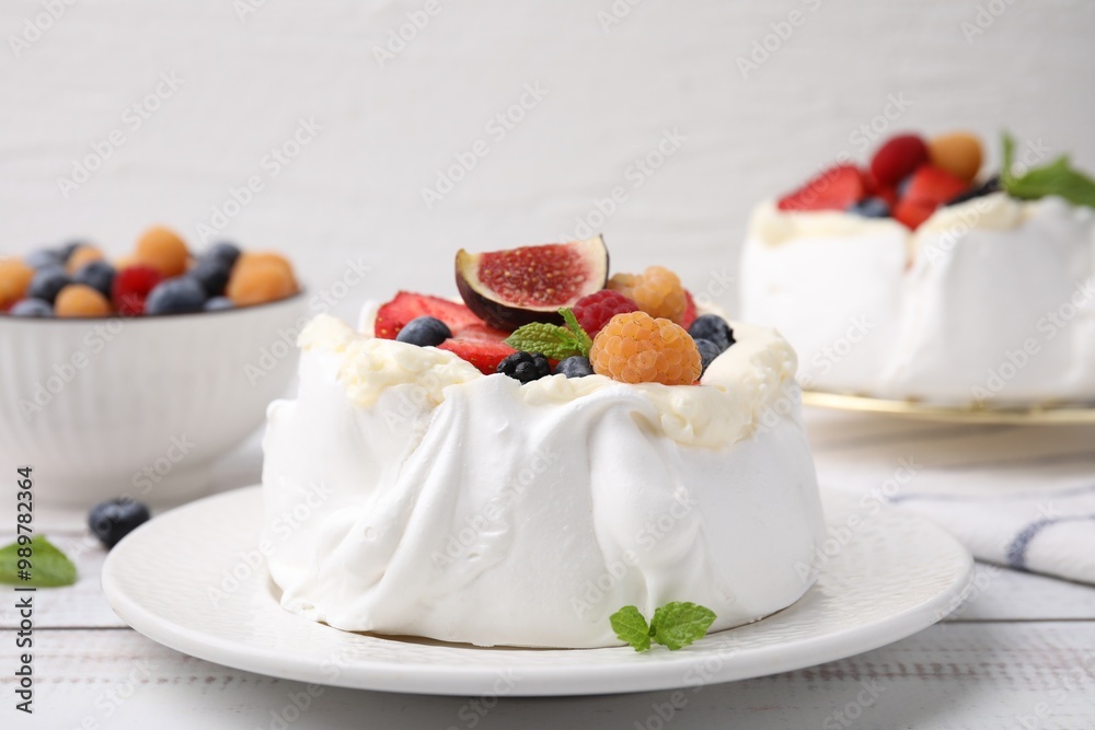 Pavlova cake (meringue dessert) with whipped cream, fresh berries, fig and mint on white wooden table, closeup Pavlova cake (meringue dessert) with whipped cream, fresh berries, fig and mint on white wooden table, closeup