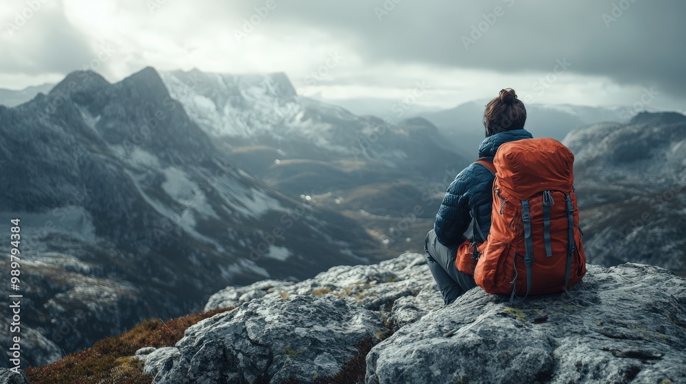 Hiker resting on a rocky outcrop, enjoying the mountain view Hiker resting on a rocky outcrop, enjoying the mountain view