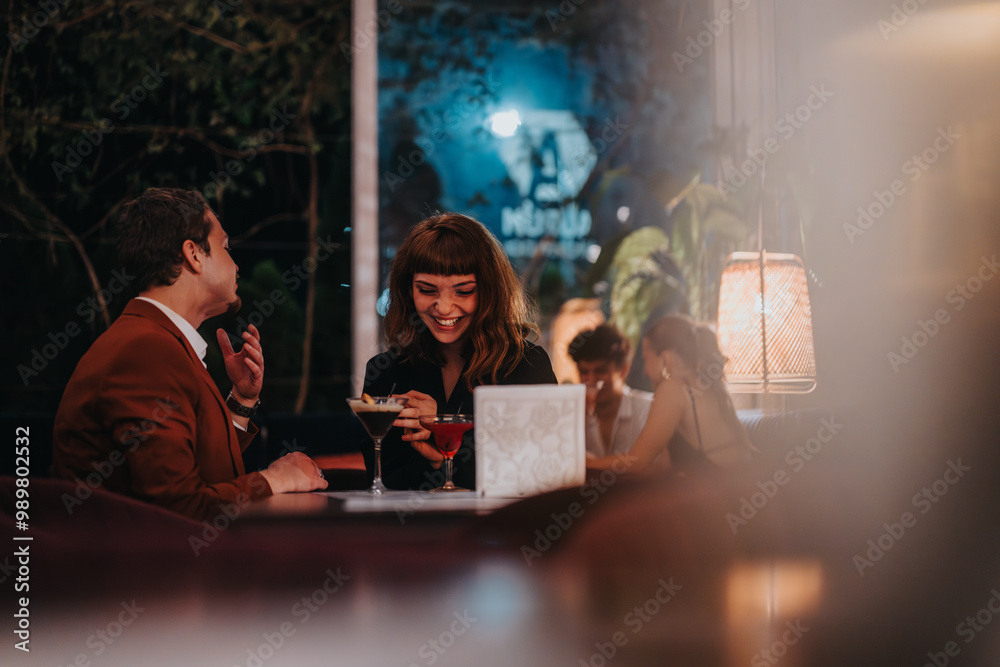 © qunica.com - A joyful couple shares an evening at a stylish restaurant, enjoying drinks and heartfelt conversation. Warm lighting creates a cozy and romantic atmosphere. © qunica.com - A joyful couple shares an evening at a stylish restaurant, enjoying drinks and heartfelt conversation. Warm lighting creates a cozy and romantic atmosphere.