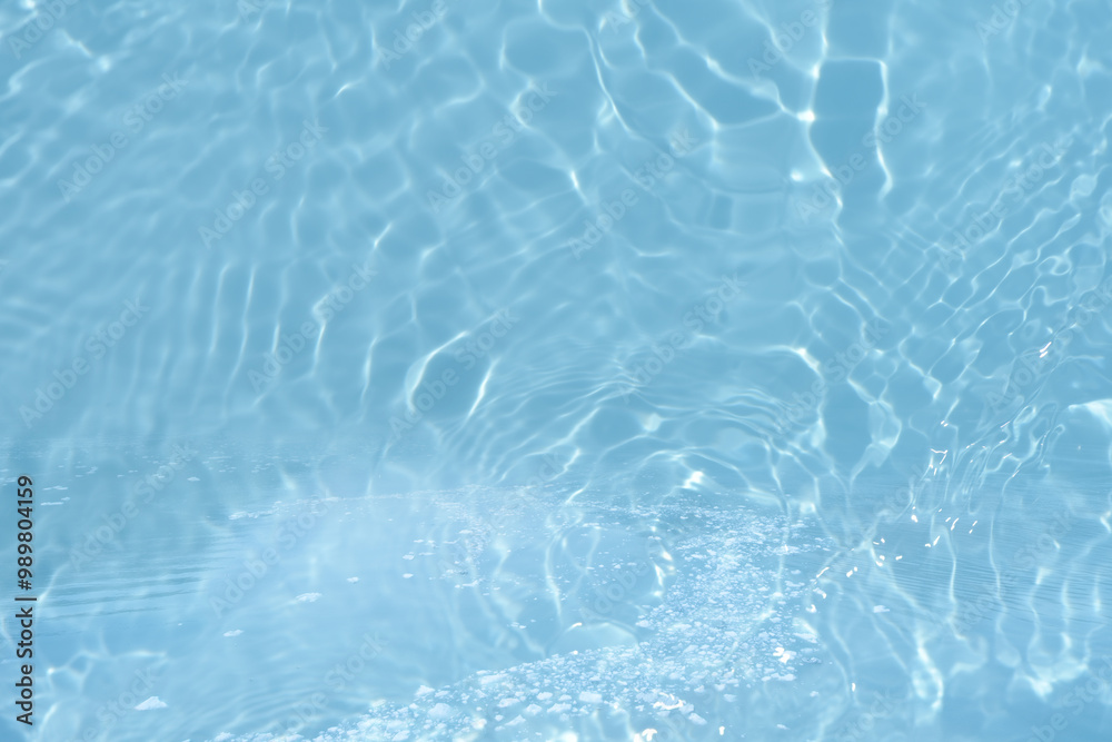 Obraz premium Blue water with ripples on the surface. Defocus blurred transparent blue colored clear calm water surface texture with splashes and bubbles. Water waves with shining pattern texture background.