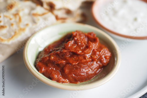 Delicious and spicy red chili sauce served alongside fresh flatbread and a creamy yogurt dip