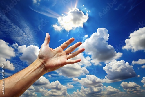 Hand Reaching Towards Soft White Clouds in a Bright Blue Sky Symbolizing Dreams and Aspirations photo