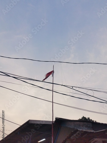 Broken Indonesian Nationality Flag at the rooftop of civilian house photo