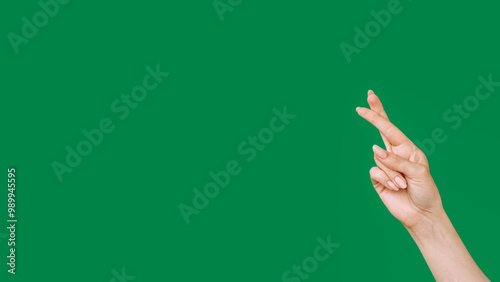 Crossed fingers. Good luck. Exciting expectation. Female hand showing hope superstitious gesture isolated on green empty space background.