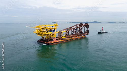 Big Construction on ship. Tender Drilling Oil Rig on Barge Ship transportation Rid to Oil Rig in The Middle of The Ocean. Five Tug boat pulling Construction photo