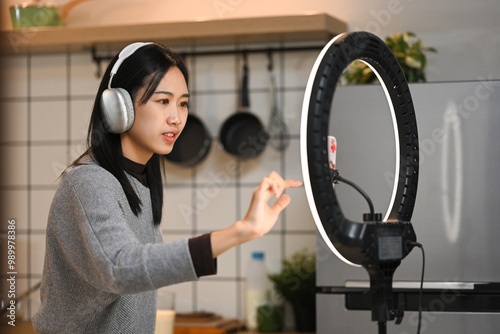 Cheerful young woman dancing and recording a video for social media on smartphone photo