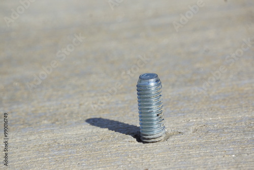 Shiny silver screw in sidewalk