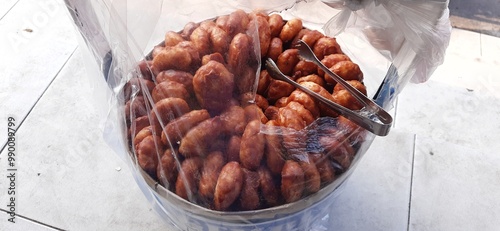 A man is selling gemblong cakes at a traditional market. Gemblong made from sticky rice coating with hot palm sugar and serve until dry. Indonesian popular sweet food  photo