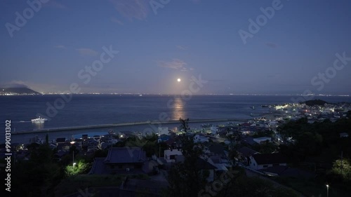 Super moon reflection on water as ferry cruises into port at twilight