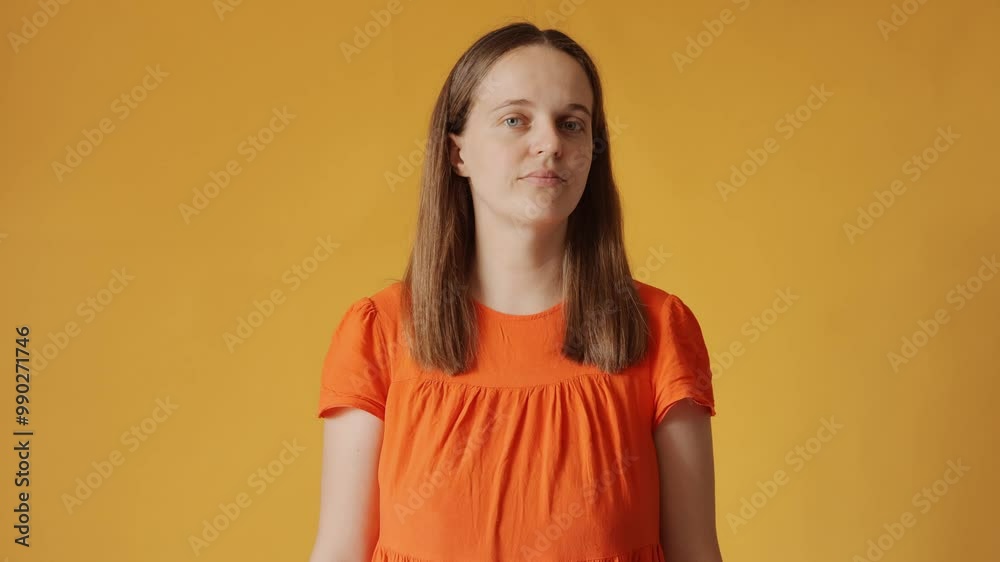 Indifferent uncertain woman in orange shirt has doubtful expression shrugging her shoulders avoiding question nodding no isolated over yellow background Indifferent uncertain woman in orange shirt has doubtful expression shrugging her shoulders avoiding question nodding no isolated over yellow background