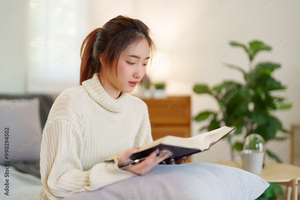 Young asian women in sweater sitting on comfortable couch to enjoying and happiness with reading literature book while relaxation and doing activity to spending time with slow life lifestyle at home Young asian women in sweater sitting on comfortable couch to enjoying and happiness with reading literature book while relaxation and doing activity to spending time with slow life lifestyle at home