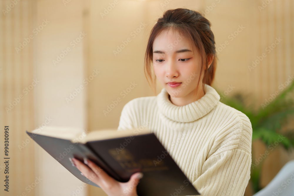 Young asian women in sweater reading a book and learning about literature story with enjoying while sitting on couch to relaxation and doing activity to spending time with slow life lifestyle at home Young asian women in sweater reading a book and learning about literature story with enjoying while sitting on couch to relaxation and doing activity to spending time with slow life lifestyle at home