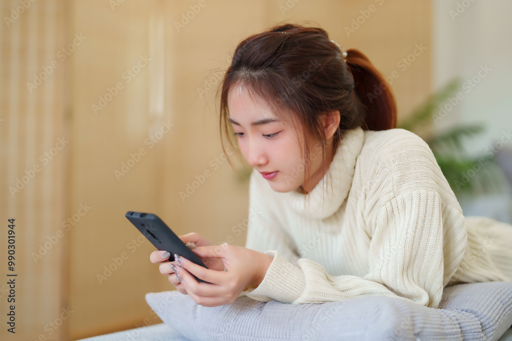 Young asian women in sweater lying on comfortable couch to enjoying with chatting social media on smartphone while relaxation and doing activity to spending time with slow life lifestyle at home Young asian women in sweater lying on comfortable couch to enjoying with chatting social media on smartphone while relaxation and doing activity to spending time with slow life lifestyle at home