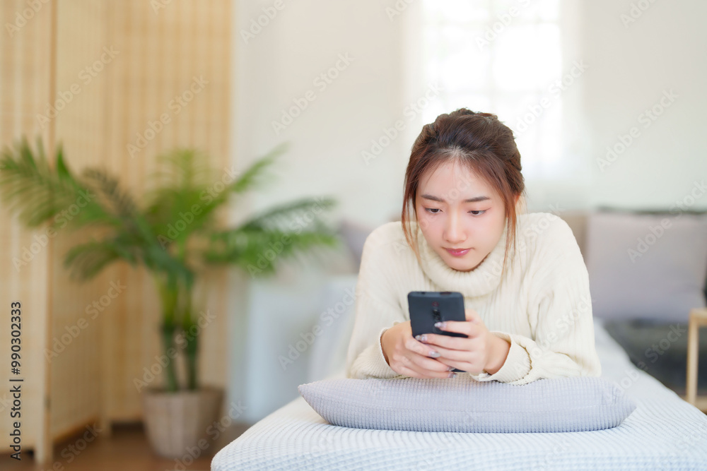 Young asian women in sweater lying on comfortable couch to enjoying with chatting social media on smartphone while relaxation and doing activity to spending time with slow life lifestyle at home Young asian women in sweater lying on comfortable couch to enjoying with chatting social media on smartphone while relaxation and doing activity to spending time with slow life lifestyle at home
