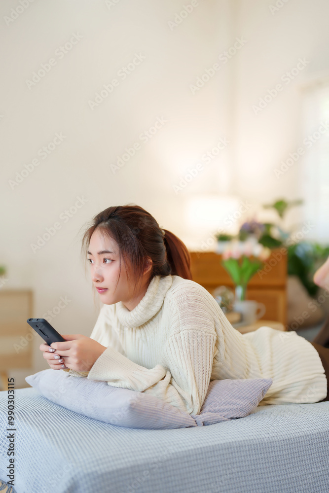 Young asian women in sweater lying on comfortable couch to enjoying with surfing entertainment on smartphone while relaxation and doing activity to spending time with slow life lifestyle at home Young asian women in sweater lying on comfortable couch to enjoying with surfing entertainment on smartphone while relaxation and doing activity to spending time with slow life lifestyle at home