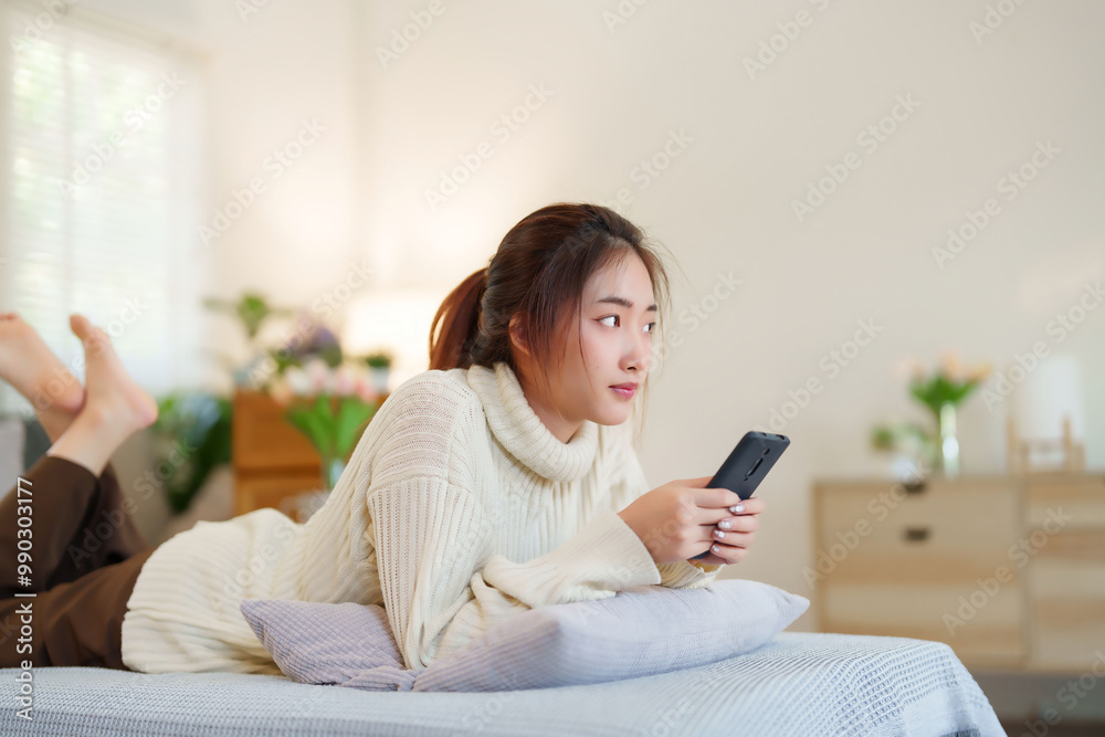 Young asian women in sweater lying on comfortable couch to enjoying with surfing entertainment on smartphone while relaxation and doing activity to spending time with slow life lifestyle at home Young asian women in sweater lying on comfortable couch to enjoying with surfing entertainment on smartphone while relaxation and doing activity to spending time with slow life lifestyle at home