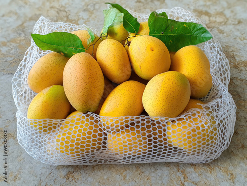 A white mesh bag containing yellow mangoes, against a white background, in the style of real photography with studio lighting. Created with AI