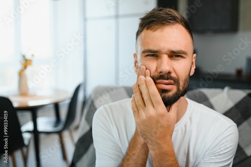 Man with sensitive teeth suffering from pain at home