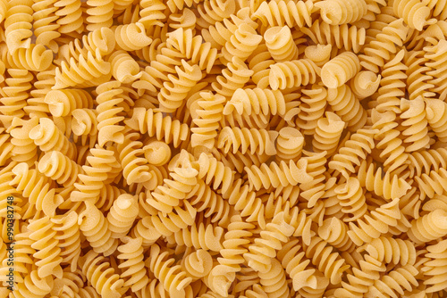 Fusilli background. A pile of yellow pasta in the shape of a spiral.