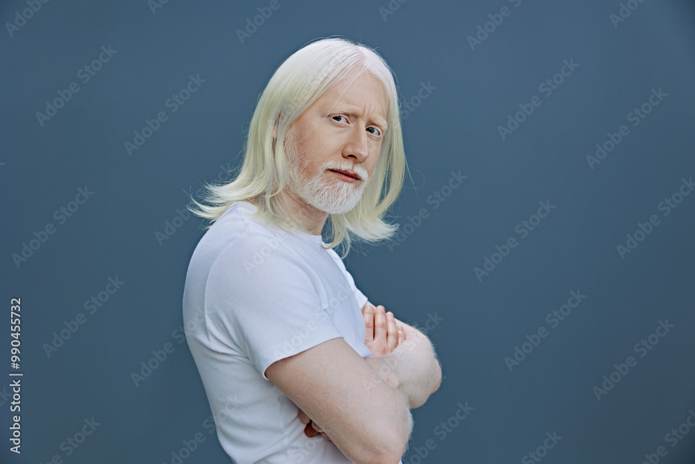 elderly man with long white hair and beard displays self confidence against a muted blue background, showcasing a calm and introspective expression and casual attire elderly man with long white hair and beard displays self confidence against a muted blue background, showcasing a calm and introspective expression and casual attire